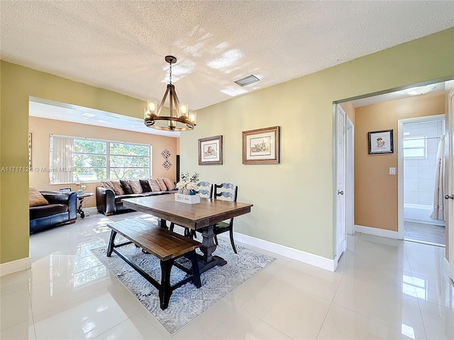 tiled dining room featuring a textured ceiling and a notable chandelier