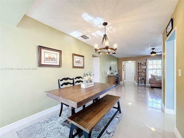 tiled dining room featuring ceiling fan with notable chandelier and a textured ceiling