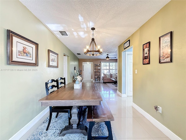 tiled dining room featuring ceiling fan with notable chandelier and a textured ceiling