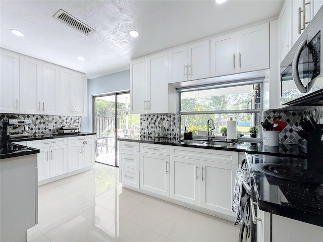 kitchen featuring a wealth of natural light, sink, white cabinets, and appliances with stainless steel finishes