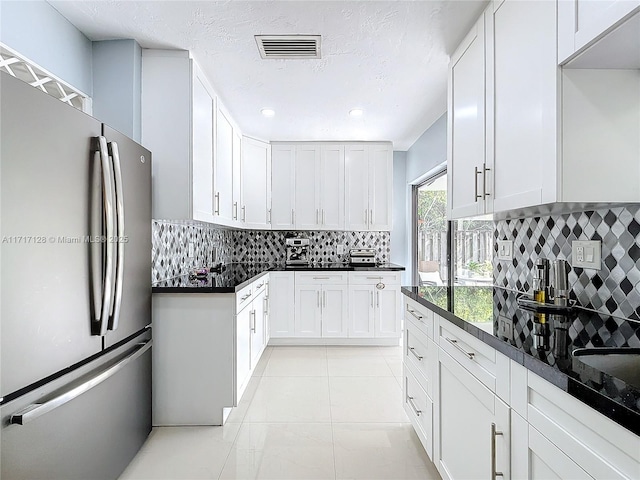 kitchen with tasteful backsplash, stainless steel fridge, white cabinets, and light tile patterned floors