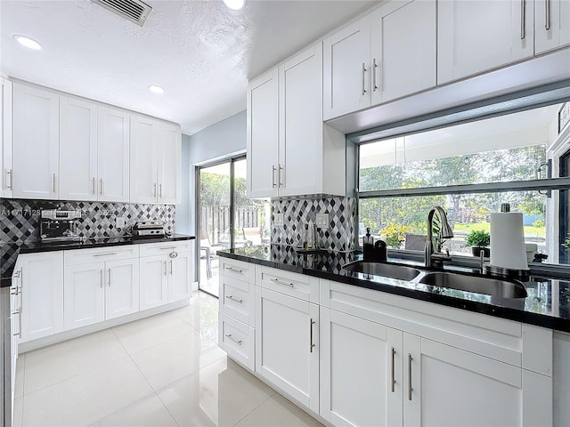 kitchen with white cabinets, sink, light tile patterned floors, tasteful backsplash, and plenty of natural light