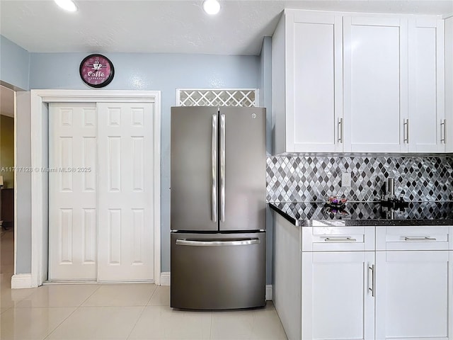 kitchen with white cabinets, tasteful backsplash, and stainless steel refrigerator