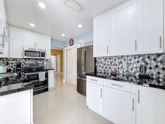 kitchen with dark stone counters, decorative backsplash, white cabinetry, and stainless steel appliances