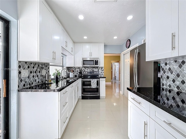 kitchen featuring decorative backsplash, dark stone counters, stainless steel appliances, sink, and white cabinets