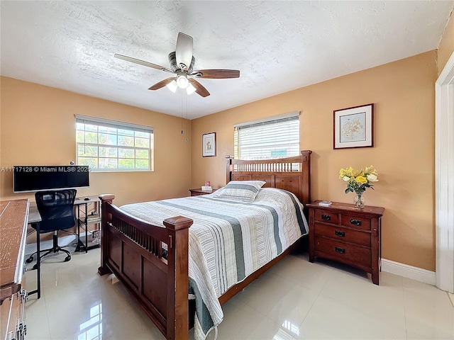 bedroom with ceiling fan, light tile patterned floors, and a textured ceiling