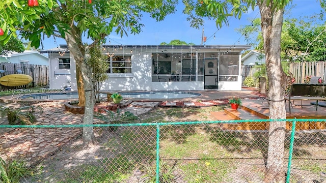 back of property with a fenced in pool and a patio