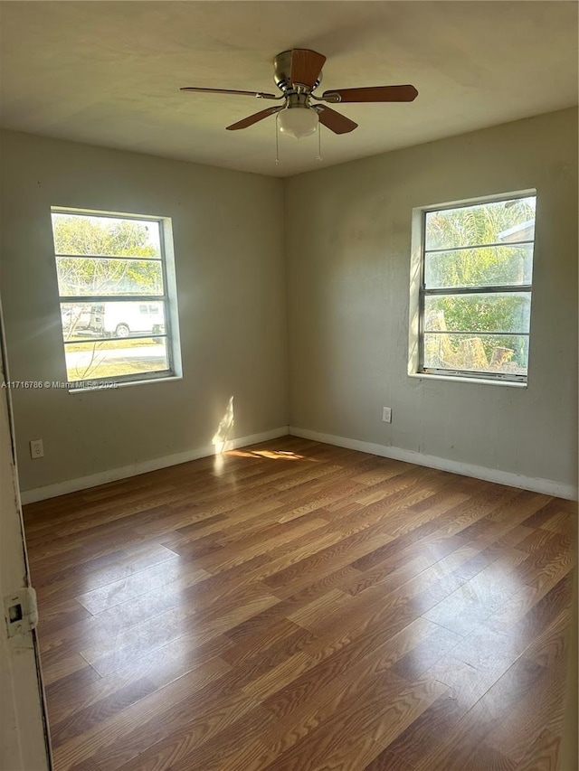 spare room featuring ceiling fan, wood-type flooring, and a wealth of natural light