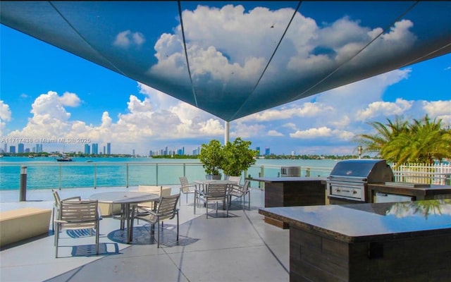 view of patio with a bar, area for grilling, a water view, and exterior kitchen