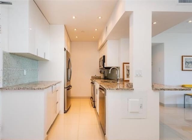 kitchen featuring light stone countertops, white cabinetry, appliances with stainless steel finishes, and light tile patterned floors