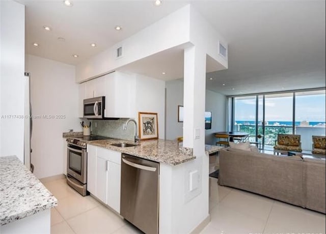 kitchen with light stone counters, sink, stainless steel appliances, and white cabinets