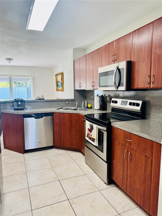 kitchen with light tile patterned flooring, stainless steel appliances, tasteful backsplash, and sink