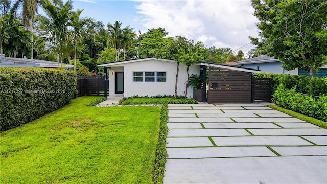 back of house featuring a gate, stucco siding, a lawn, and fence