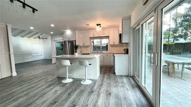 kitchen featuring stainless steel fridge, a kitchen breakfast bar, ceiling fan, hardwood / wood-style floors, and a kitchen island