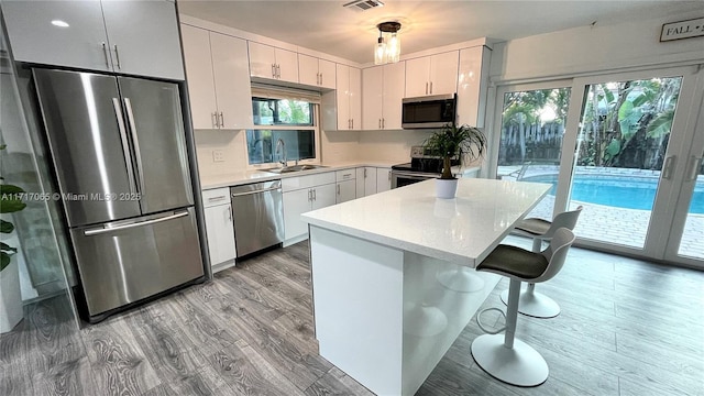 kitchen featuring a kitchen breakfast bar, white cabinetry, sink, and appliances with stainless steel finishes