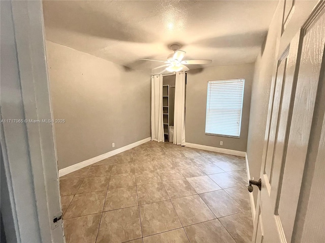 unfurnished bedroom with ceiling fan, light tile patterned flooring, and a textured ceiling