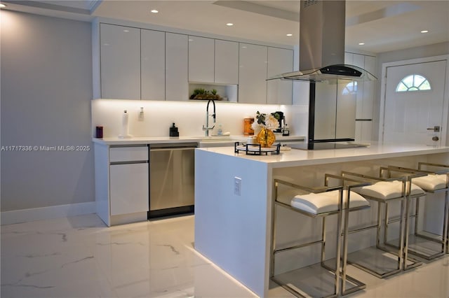 kitchen featuring dishwasher, white cabinets, sink, island range hood, and a breakfast bar area