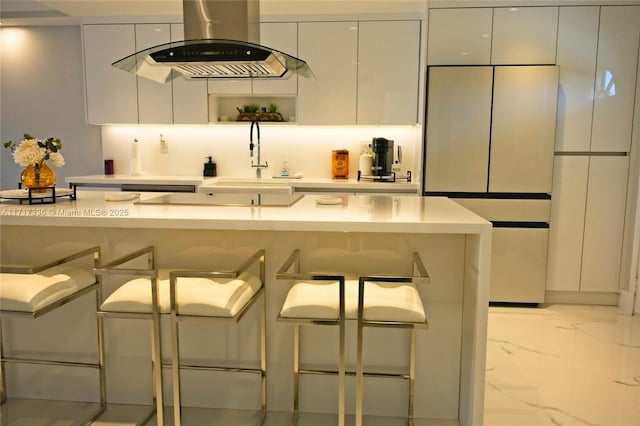 kitchen with island exhaust hood, a breakfast bar, white cabinets, and sink