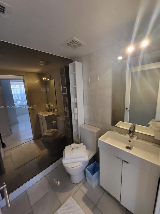 bathroom featuring tile walls, vanity, tile patterned floors, and toilet