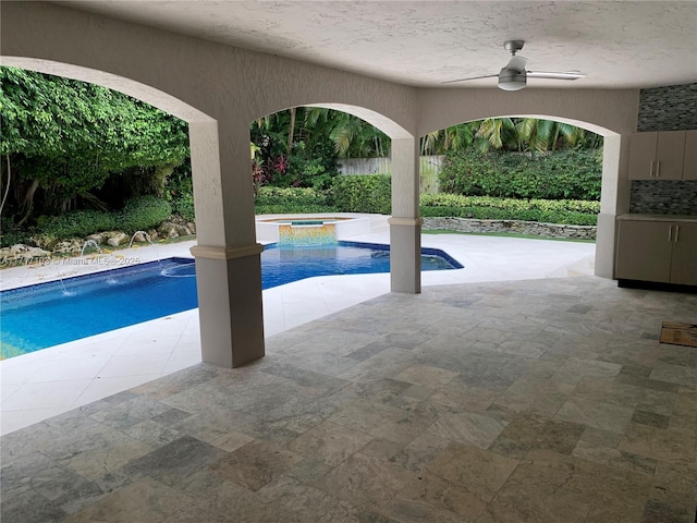 view of swimming pool with ceiling fan, an in ground hot tub, and a patio