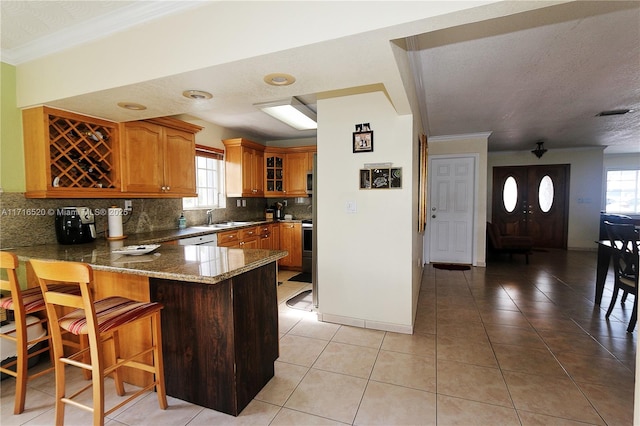 kitchen with sink, kitchen peninsula, plenty of natural light, decorative backsplash, and ornamental molding