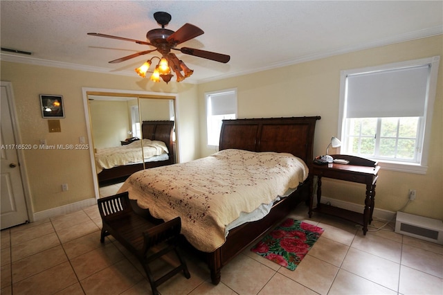 bedroom with ceiling fan, a closet, light tile patterned floors, and crown molding