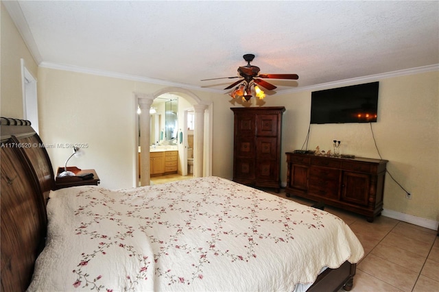 bedroom featuring ceiling fan, light tile patterned flooring, ornamental molding, and ensuite bath