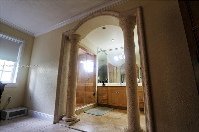 bathroom featuring ornate columns, tile patterned floors, vanity, a shower with shower door, and ornamental molding