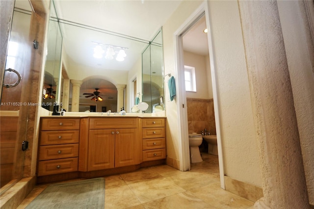 bathroom with vanity, a shower with door, ceiling fan, a bidet, and tile walls