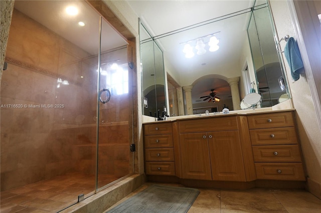 bathroom featuring ornate columns, ceiling fan, tile patterned floors, a shower with door, and vanity