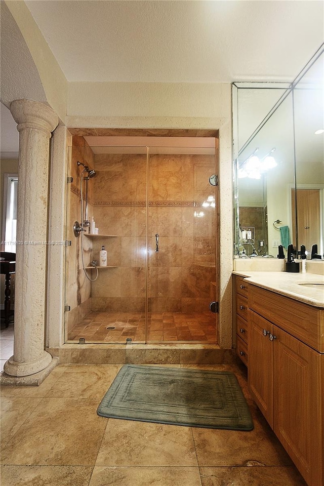 bathroom featuring tile patterned floors, vanity, ornate columns, and an enclosed shower