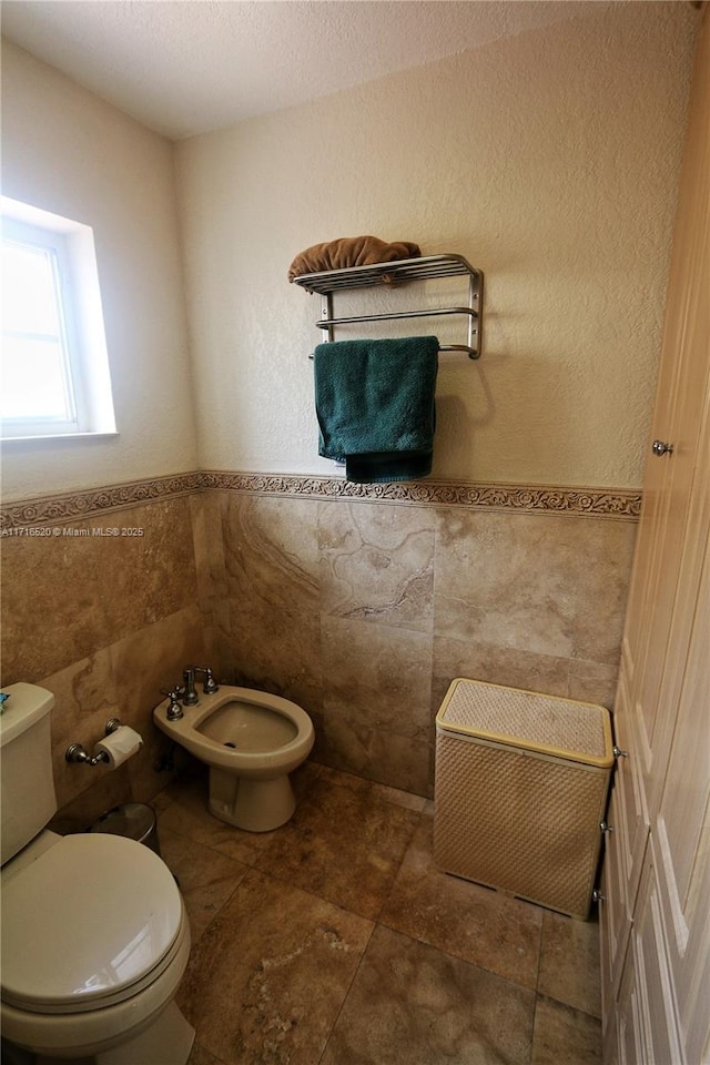 bathroom featuring a bidet, tile walls, and toilet