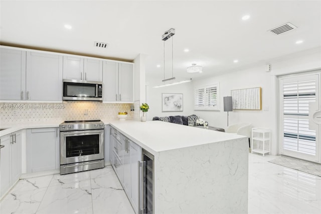 kitchen featuring white cabinetry, stainless steel appliances, kitchen peninsula, pendant lighting, and decorative backsplash