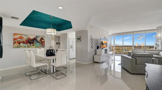 dining area featuring light tile patterned floors, a tray ceiling, a wall of windows, and a notable chandelier