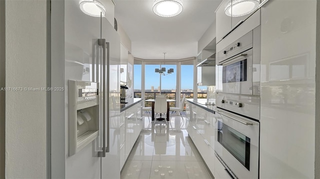 kitchen with stainless steel appliances, light tile patterned floors, pendant lighting, a wall of windows, and white cabinets