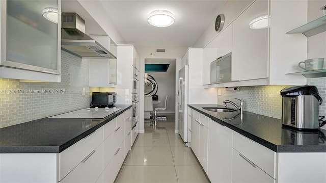 kitchen featuring light tile patterned floors, white cabinetry, white electric stovetop, and wall chimney range hood