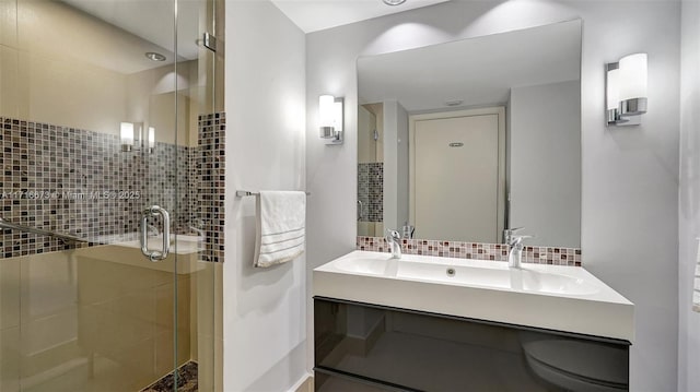 bathroom with decorative backsplash, vanity, and a shower with shower door