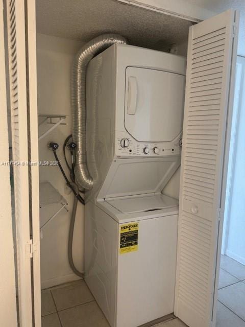 washroom featuring light tile patterned flooring and stacked washing maching and dryer