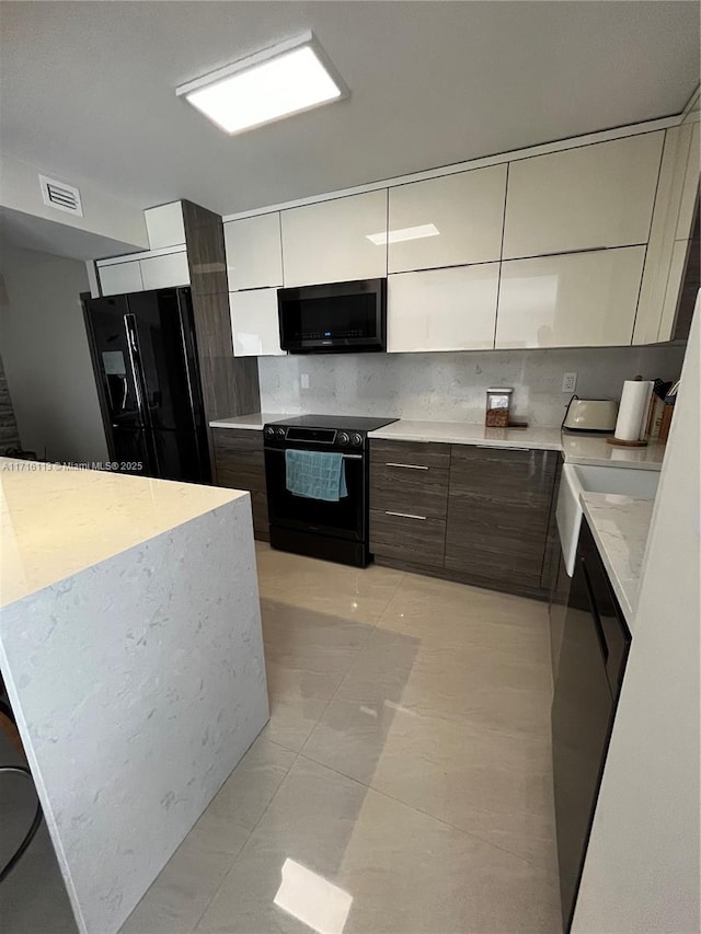 kitchen with black appliances, white cabinetry, light tile patterned floors, and tasteful backsplash