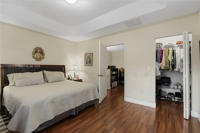 bedroom with a spacious closet, a closet, and dark wood-type flooring