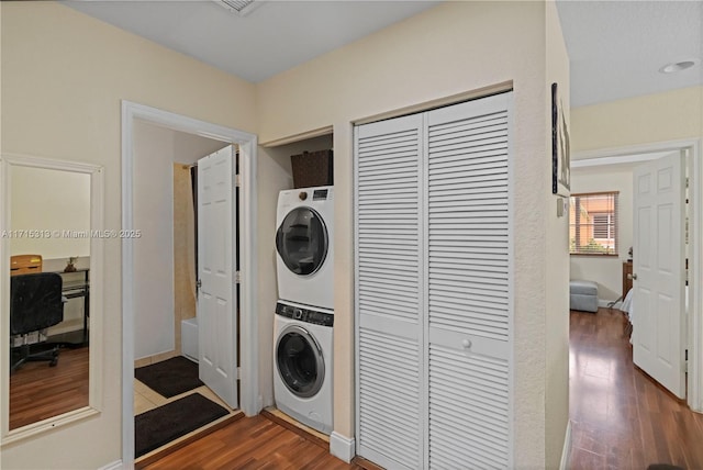 washroom with dark hardwood / wood-style flooring and stacked washer and dryer