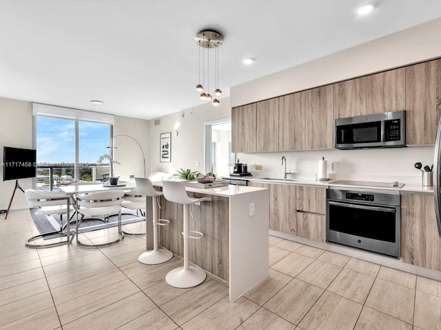 kitchen with pendant lighting, a center island, sink, light tile patterned floors, and stainless steel appliances