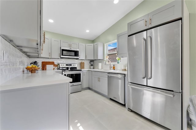 kitchen featuring appliances with stainless steel finishes, gray cabinets, vaulted ceiling, and tasteful backsplash