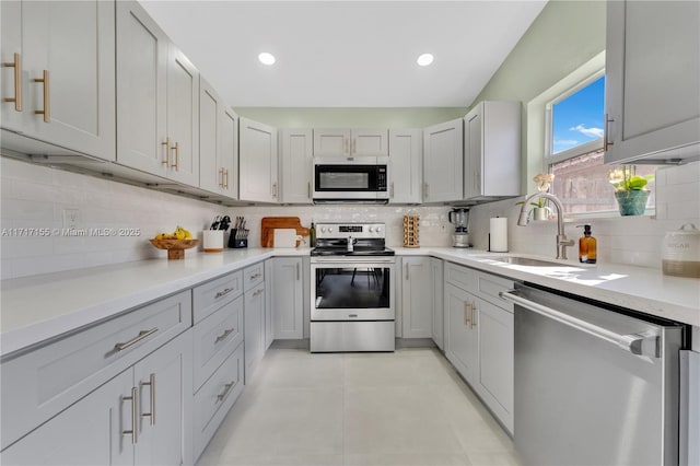 kitchen with tasteful backsplash, gray cabinets, sink, and appliances with stainless steel finishes