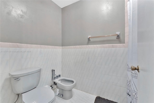 bathroom with tile patterned flooring, a bidet, tile walls, and toilet