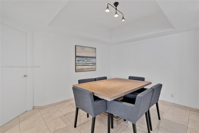 tiled dining area featuring a raised ceiling