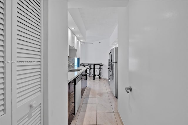 kitchen featuring sink, white cabinets, stainless steel appliances, and light tile patterned floors