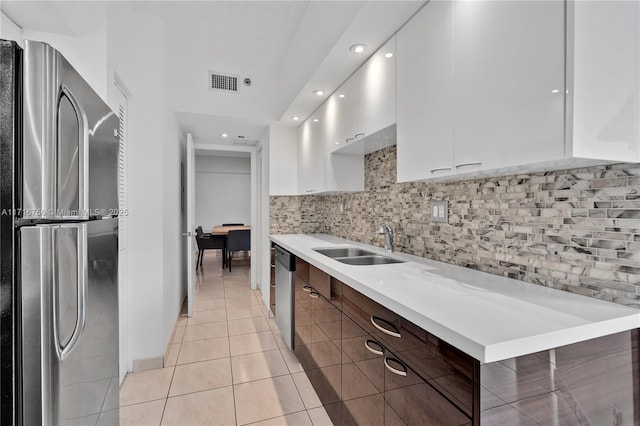 kitchen with appliances with stainless steel finishes, dark brown cabinetry, sink, light tile patterned floors, and white cabinets