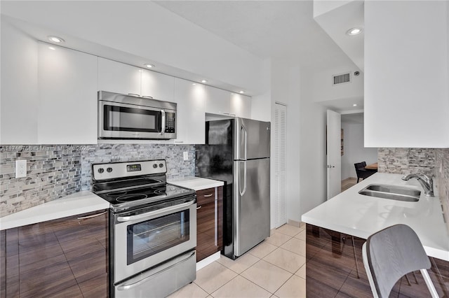 kitchen featuring white cabinets, sink, light tile patterned floors, dark brown cabinets, and stainless steel appliances