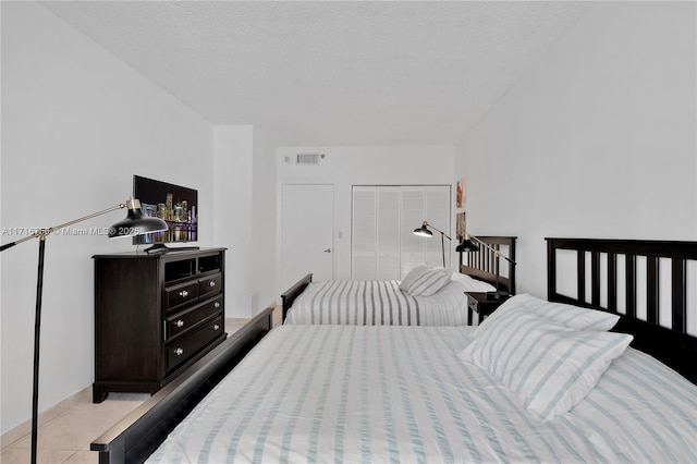 tiled bedroom featuring a textured ceiling and a closet